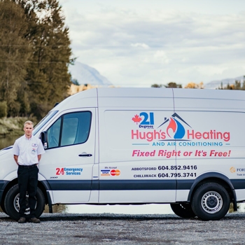 A person stands next to a white 21 Degrees Hugh's Heating and Air Conditioning truck with tall trees in the background